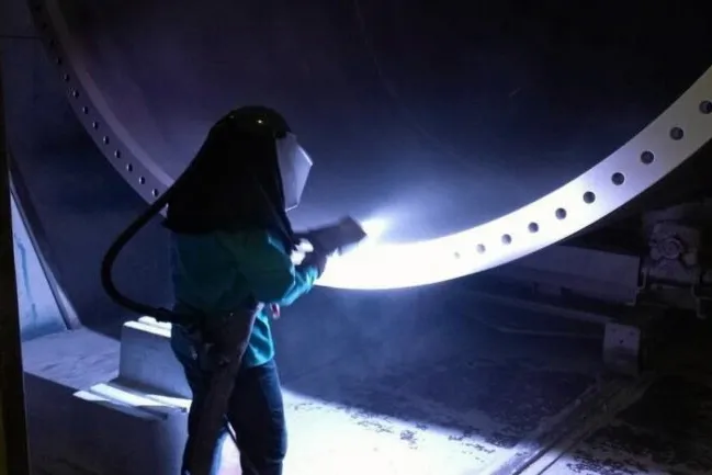 An Arcosa worker applying coating protection for a wind tower section.